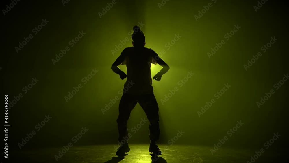 Silhouette young man dancing single in club, neon light, lots of smoke. Fashion street wear. Silhouette.