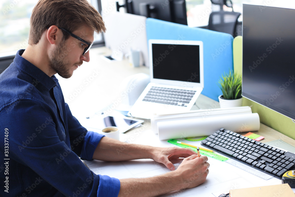 Shot of a handsome male architect working on a design in his office. Shot of a handsome male architect working on a design in his office.