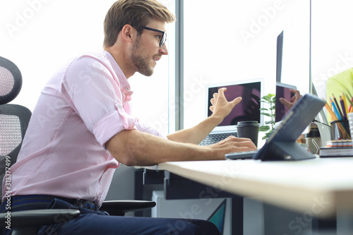 Thoughtful young business man in shirt working using computer while sitting in the office.