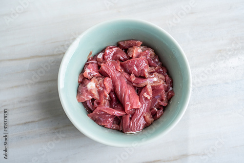 A bowl of cured beef on a kitchen tile countertop plate