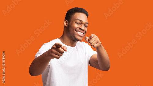 Happy black man choosing you over orange background