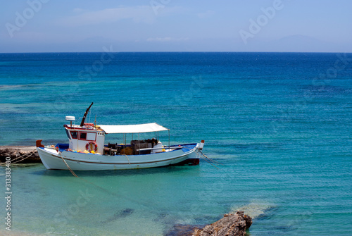 Greece, a small fishing boat moored at a quay on the island of Koufonissi. Clear blue sky, and calm seas on a summers day.  Peace and tranquility.