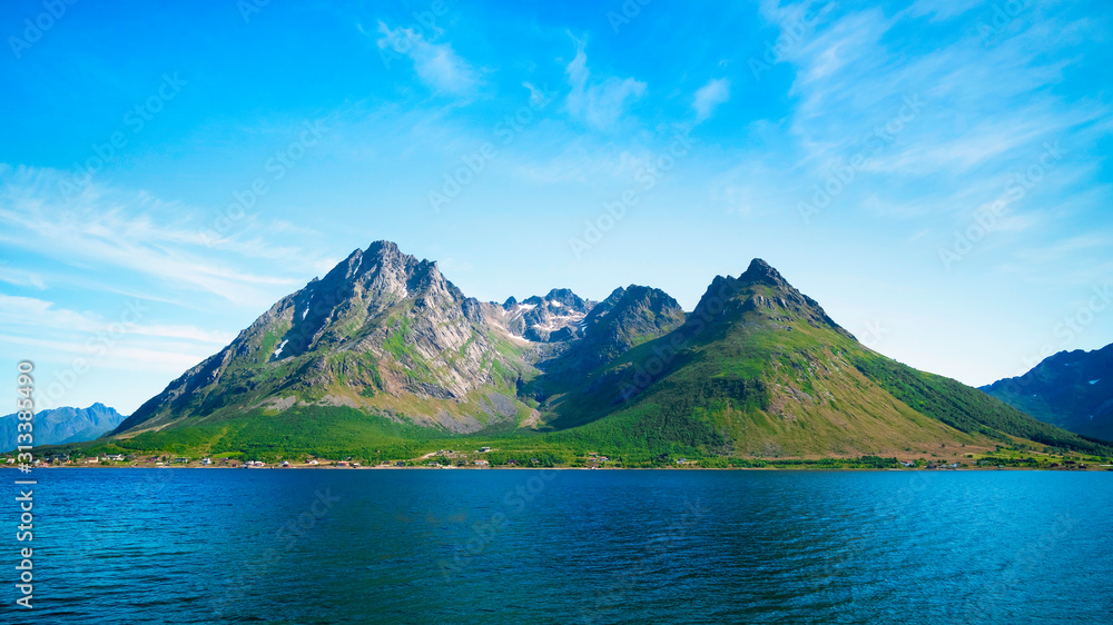 Summer landscape of Lofoten islands, Norway. Symmetrical mountain peaks, green meadows and a fjord.