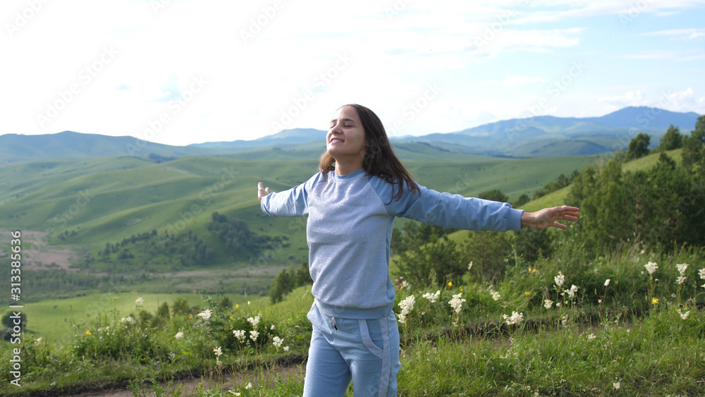 Beauty girl running and spinning on field with mountains background. Freedom concept.