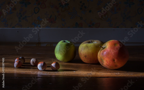 Nature morte: pommes et noisettes sur une table en bois ancienne photo