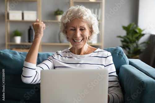 Excited aged woman feels overjoyed received great online news