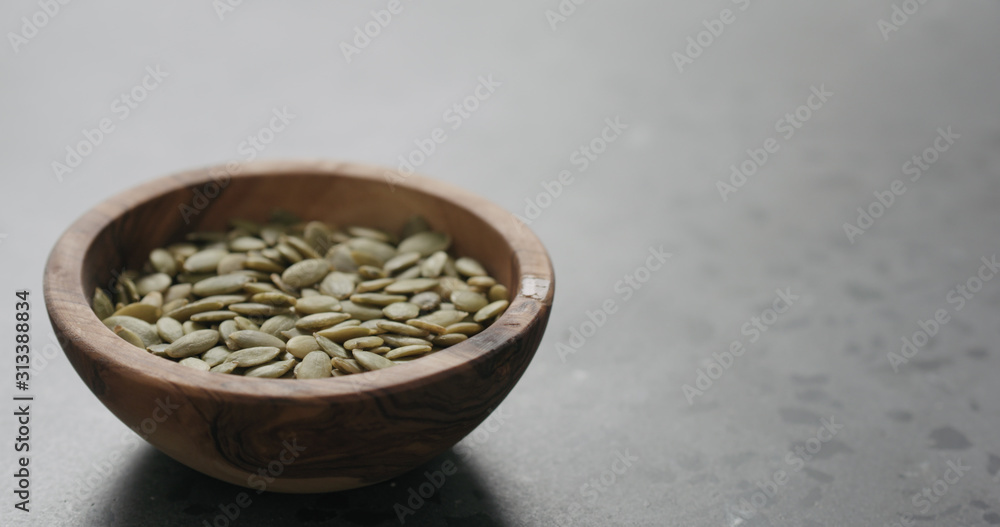 pumpkin seeds in olive bowl on terrazzo countertop with copy space pumpkin seeds in olive bowl on terrazzo countertop with copy space