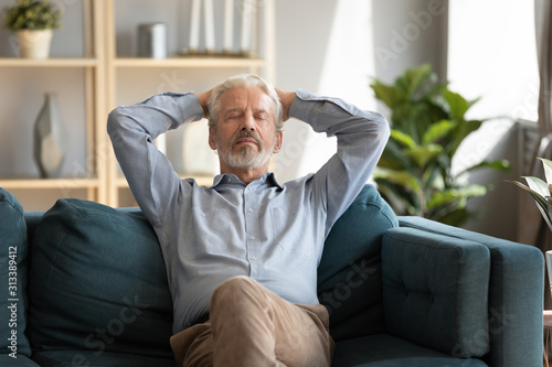 Obraz na plátně Mature man falls asleep leaned on couch in living room