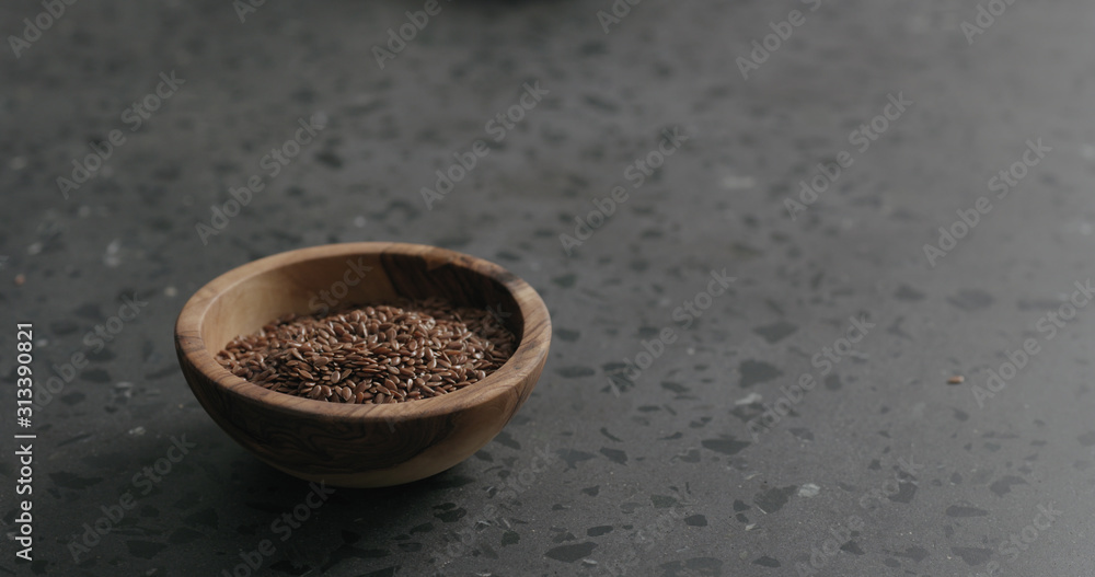 flaxseed in olive bowl on terrazzo countertop with copy space