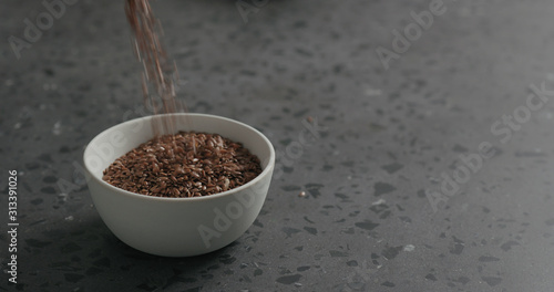 flaxseed falling into white bowl on terrazzo countertop