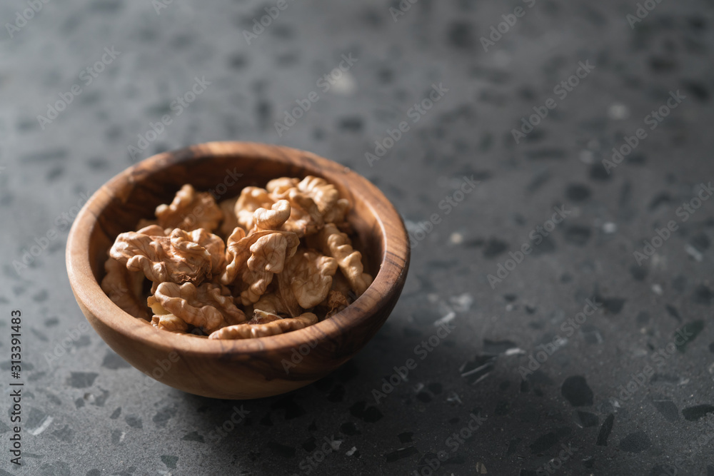 Walnuts in wooden bowl on terrazzo countertop with copy space
