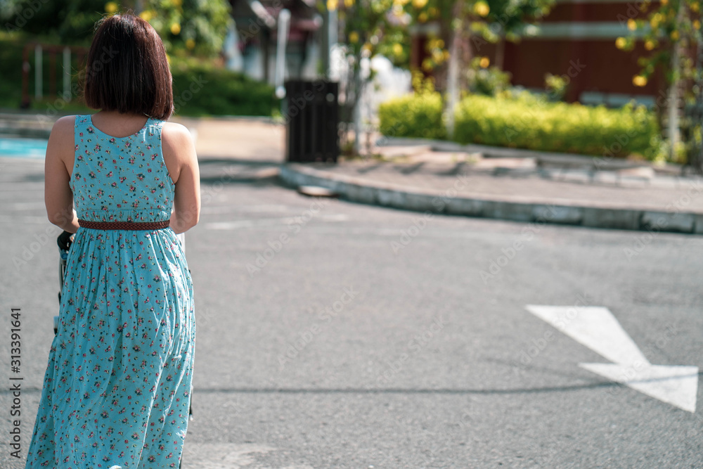 Young asian woman walking with stroller at street.