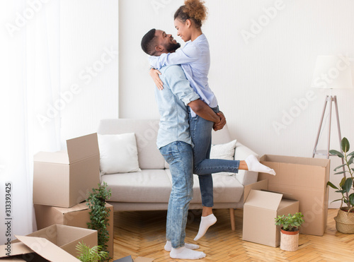 Boyfriend Lifting Girlfriend Among Moving Boxes In New House © Prostock-studio
