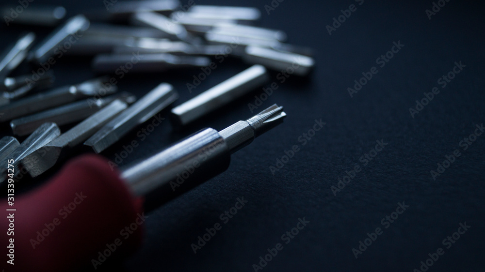 A nozzle on a small screwdriver close-up on a black background. Rear set of additional screwdrivers. A nozzle on a small screwdriver close-up on a black background. Rear set of additional screwdrivers.