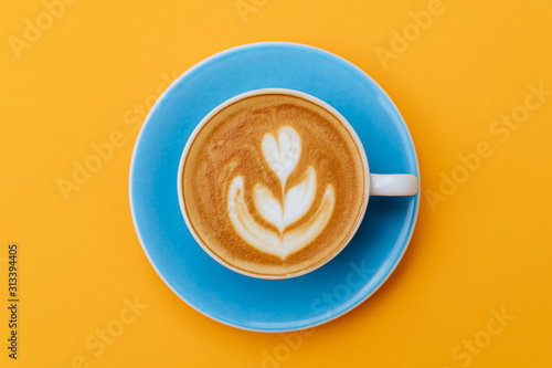 Cup of fresh coffee on blue background, top view photo