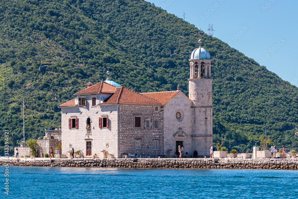 Beautiful shot of a church near the sea with a forested mountain in the background