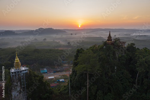 Beautiful sunrise with pagoda on the top of rock and tree with fog at Khao Na Nai Luang Dharma Park,Surat thani province,Thailand
