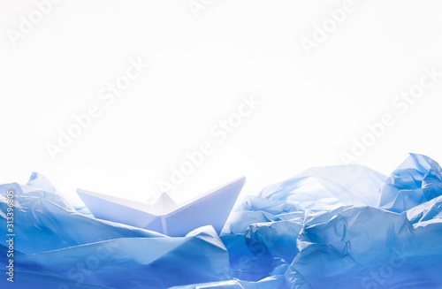 Paper boat in water of plastic bags over white background