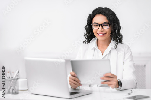Portrait of busy hispanic girl using tablet and computer