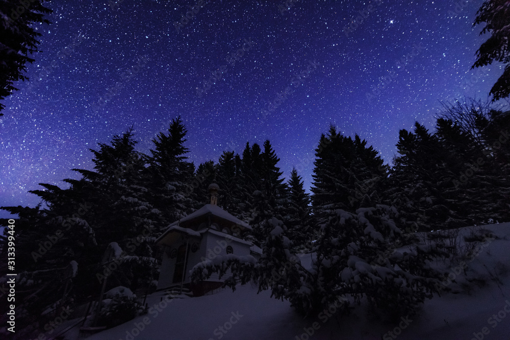 Fototapeta premium Fairytale landscapes of the winter Carpathian Mountains with a charming milky way in the sky tourist tents and snowy houses in the valleys 