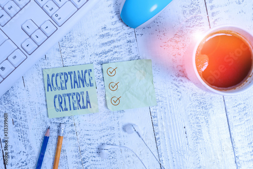 Conceptual hand writing showing Acceptance Criteria. Concept meaning Specified indicators in assessing the ability of a part Writing equipment and computer stuff plus drinks on wooden table