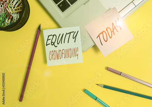 Conceptual hand writing showing Equity Crowdfunding. Concept meaning raising capital used by startups and earlystage company Laptop sticky notes container pencils markers colored background photo