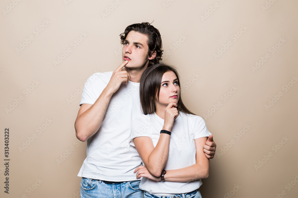 Young couple holding chins and being concentrated on their problems isolated on beige background Young couple holding chins and being concentrated on their problems isolated on beige background