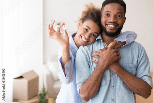 Afro Spouses Showing Key To Camera Embracing In New Home photo