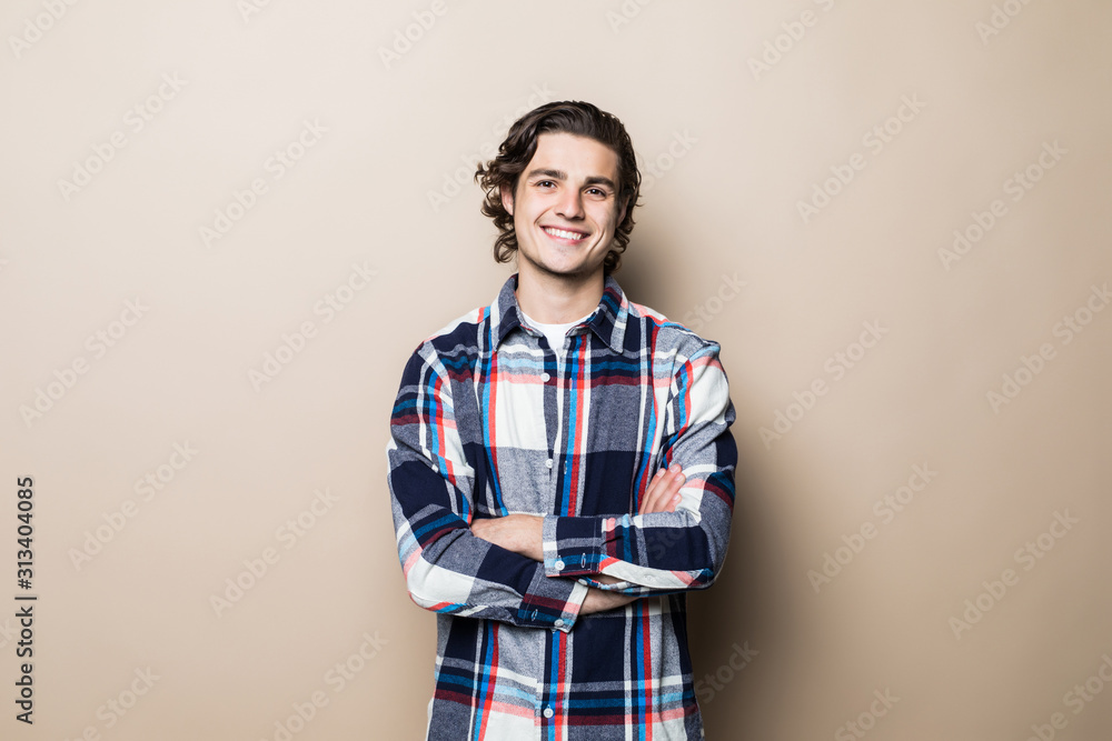 Happy smiling handsome man with crossed arms looking to camera over beige background. Emotions concept Happy smiling handsome man with crossed arms looking to camera over beige background. Emotions concept