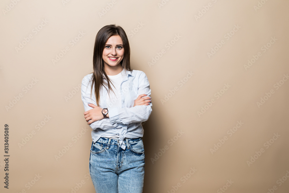 Charming brunette woman standing with hands folded, looking at camera, isolated over beige background Charming brunette woman standing with hands folded, looking at camera, isolated over beige background