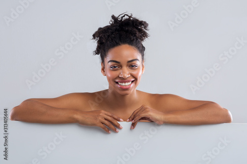 Smiling black nude woman posing over grey background