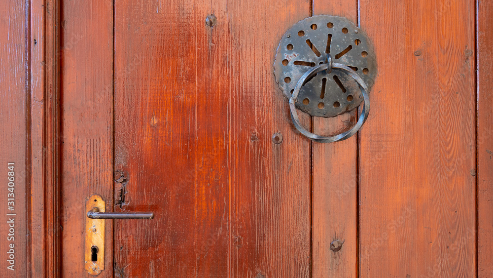 Old metal door handle knocker on a wooden door with handle. Old metal door handle knocker on a wooden door with handle.