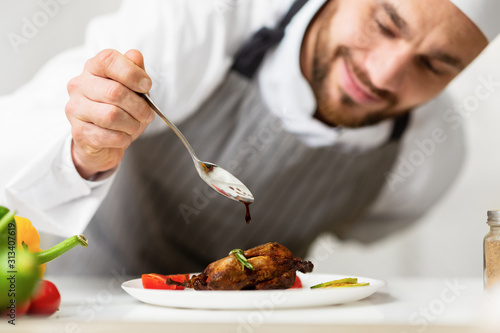 Cook Man Pouring Sauce On Chicken Plating Dish In Kitchen photo