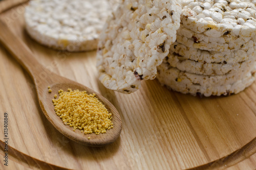 Soy lecithin in a wooden spoon on a wooden backgroundand round multigrain rice cakes.