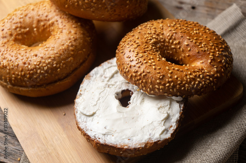 Sesame bagels with spreadable cream cheese on wooden background © Guajillo studio