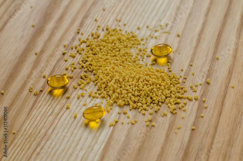 Soy lecithin granules and gel pills capsule on a wooden background.