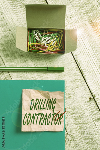 Conceptual hand writing showing Drilling Contractor. Concept meaning contract their services mainly for drilling wells Wrinkle paper and cardboard placed above wooden background photo