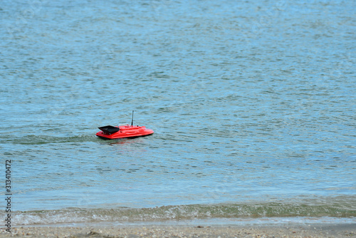 A radio-controlled toy boat floats on the sea.