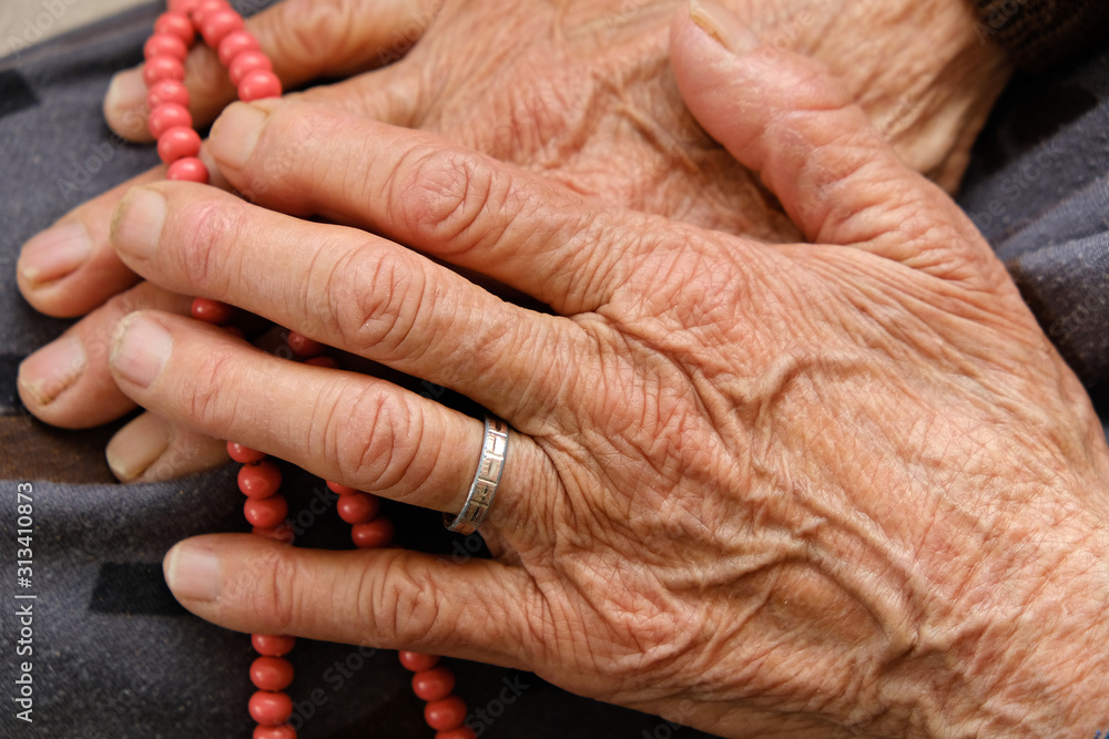 Fototapeta premium old woman with ring on her finger worships her hand with rosary,