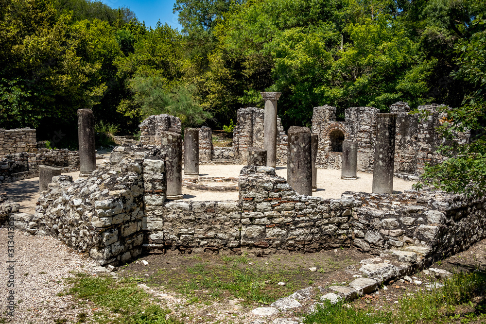 Ruined round ritual place with columns. Beautiful warm spring day and archeological ruins at Butrint National Park, Albania, UNESCO heritage. Travel photography with fresh green flora