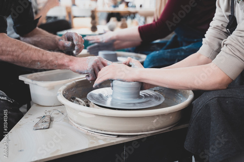 Craftsman teaching boy how to molding clay pot on pottery wheel crafts hobby workshop