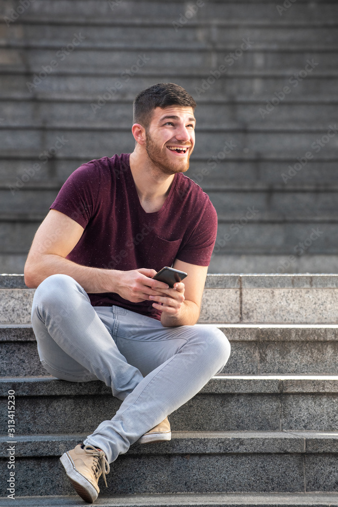 young man sitting on steps outside with cellphone young man sitting on steps outside with cellphone