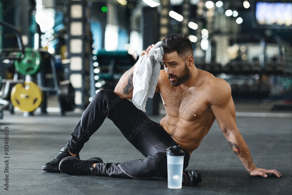 Handsome athlete wiping sweat after workout at gym - obrazy, fototapety, plakaty 