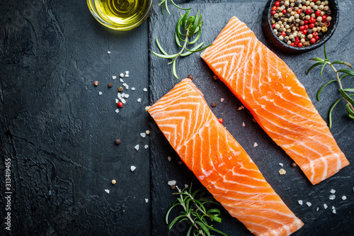 Raw salmon fillet and ingredients for cooking, seasonings and herbs on a dark background . Top view photo