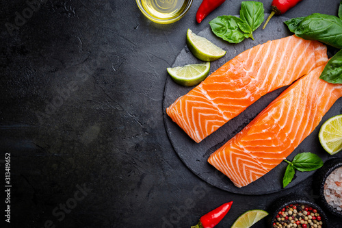Foto Raw salmon fillet and ingredients for cooking, seasonings and herbs on a dark background