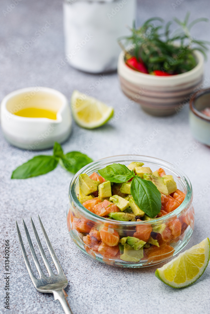 Delicious avocado and raw salmon salad, tartare, served glass jar with lime, light background Delicious avocado and raw salmon salad, tartare, served glass jar with lime, light background