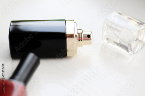 defocused perfume bottle and red nail polish on white table