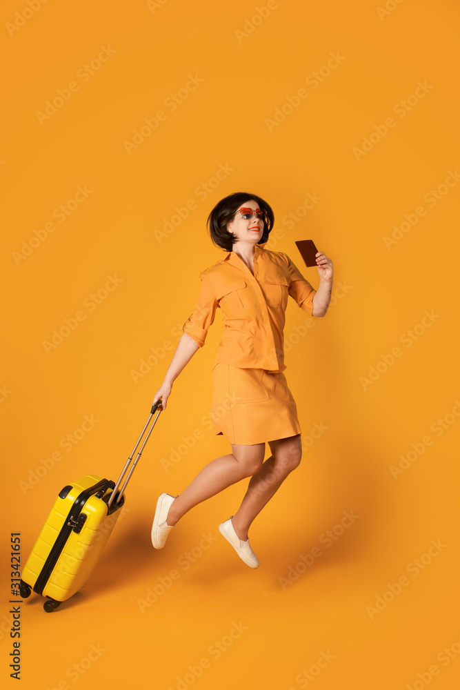 Full length portrait of pretty woman jumping with yellow suitcase. Happy girl traveler having fun Full length portrait of pretty woman jumping with yellow suitcase. Happy girl traveler having fun