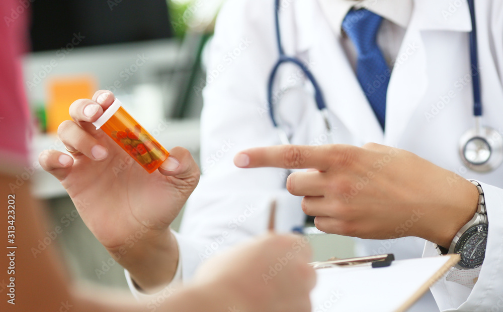 Close-up of doctor's hand holding medicine and giving it to his patient. Close-up of doctor's hand holding medicine and giving it to his patient.