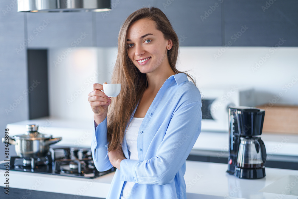Portrait of happy attractive woman drinking and enjoying hot fresh aromatic coffee after brewing coffee using coffee maker in the kitchen at home Portrait of happy attractive woman drinking and enjoying hot fresh aromatic coffee after brewing coffee using coffee maker in the kitchen at home
